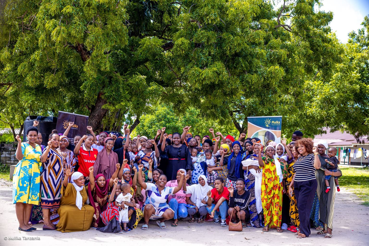 A YEE youth cohort celebrating together under the trees in Dar es Salaam